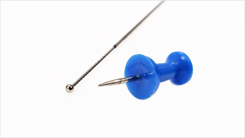 Sava's mechanical cable assembly with a ball end fitting next to a pushpin.